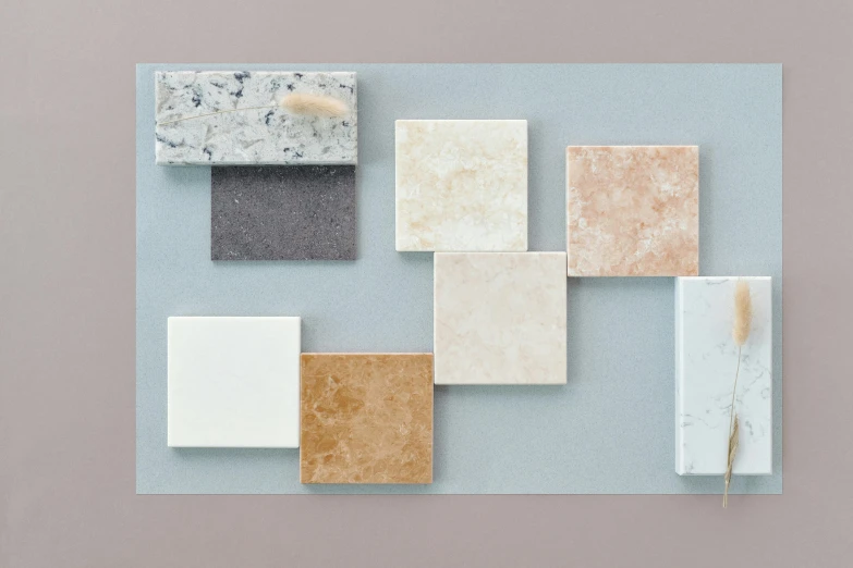 a group of different colored tiles sitting on top of a blue surface, inspired by David Chipperfield, cream and white color scheme, granite, album, amber