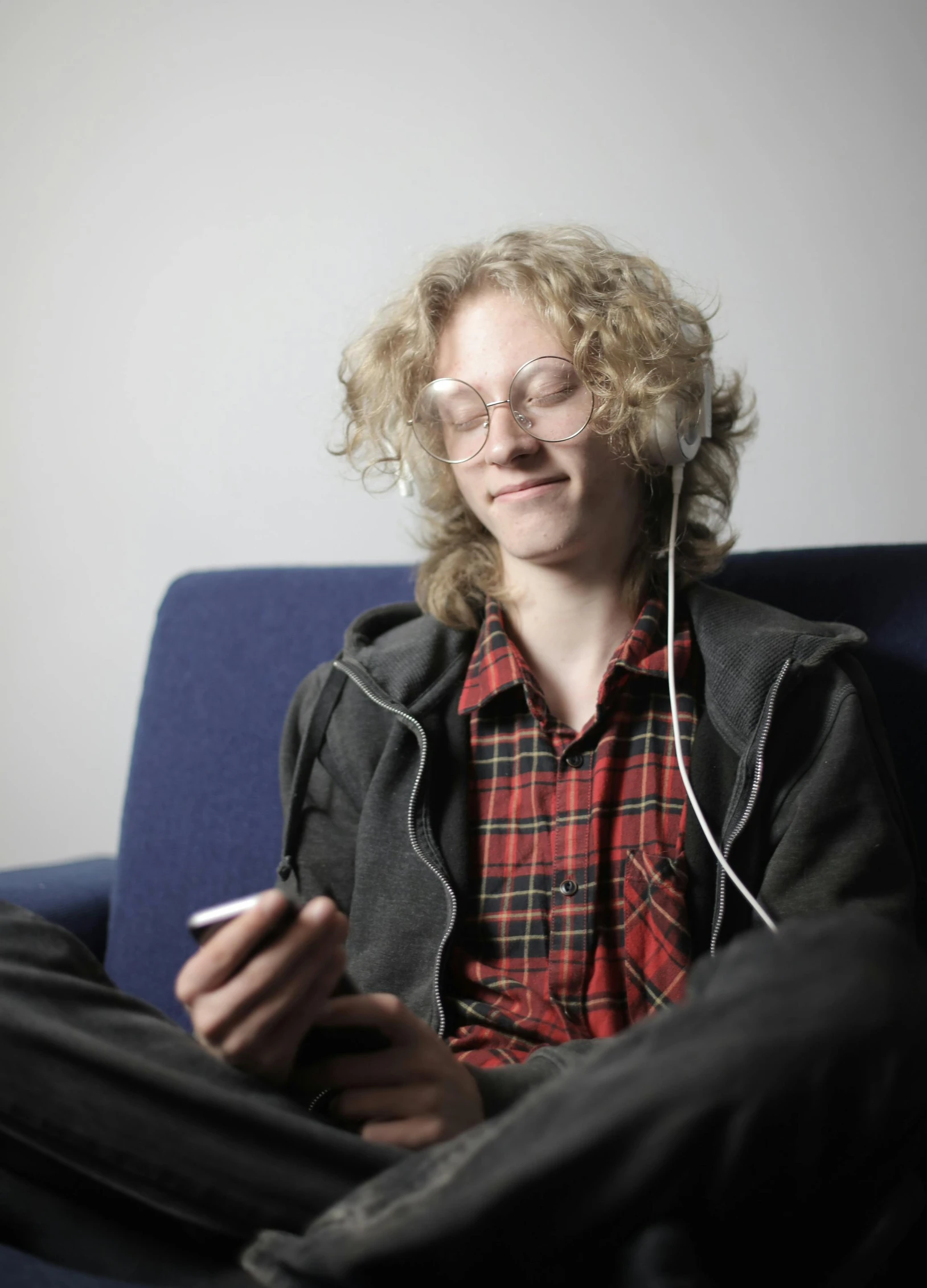 a man sitting on a couch listening to music, happening, pale skin curly blond hair, very nerdy, in 2 0 1 2, earbuds