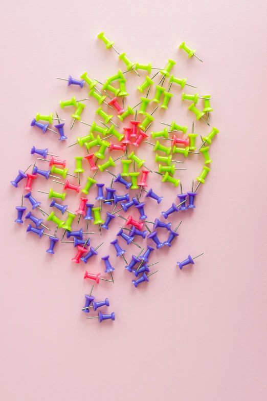 a pile of pins sitting on top of a pink surface, pexels, ((neon colors)), lime and violet, paper, studs