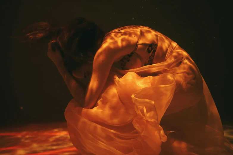 a woman in a white dress under water, an album cover, inspired by Elsa Bleda, unsplash contest winner, coloured in orange fire, draped in silky gold, ignant, rinko kawauchi