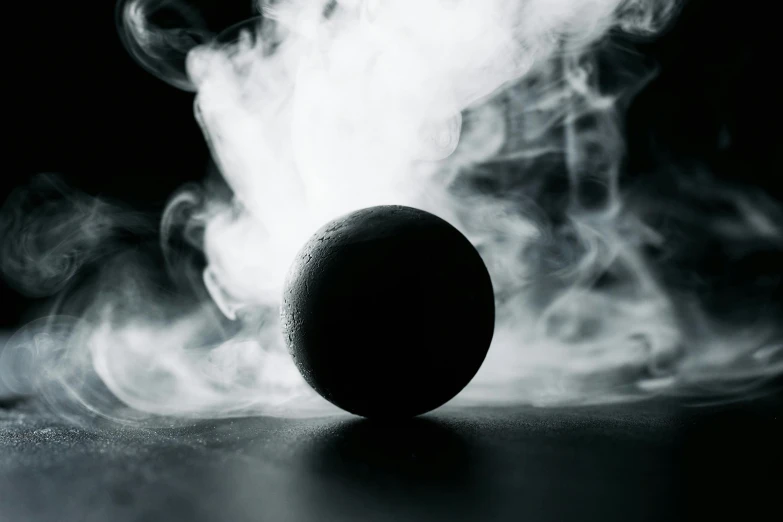 a black egg sitting on top of a table covered in smoke, by Matthias Stom, pexels contest winner, sphere, black circle, cannonballs, instagram post