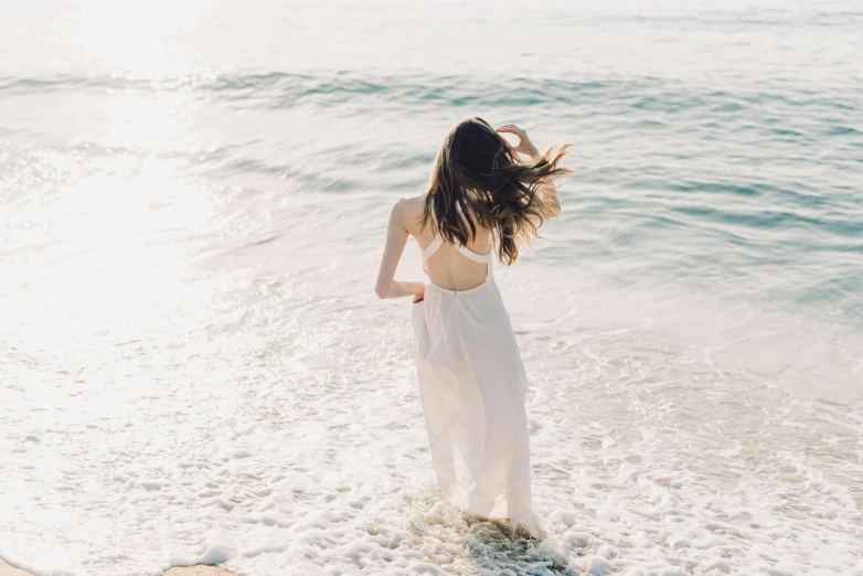 a woman standing on top of a beach next to the ocean, flowing white dress, unsplash transparent, her loose hair, instagram post