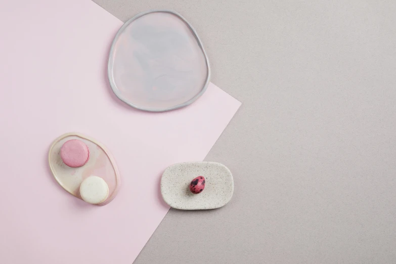 a couple of plates sitting on top of a table, inspired by Anish Kapoor, minimalism, pink pastel, floating stones, silicone skin, miniature product photo