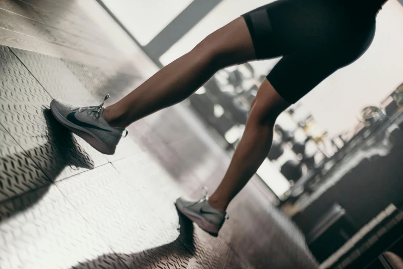 a close up of a person's legs on a skateboard, trending on pexels, in a gym, tights; on the street, wearing black shorts, girl running
