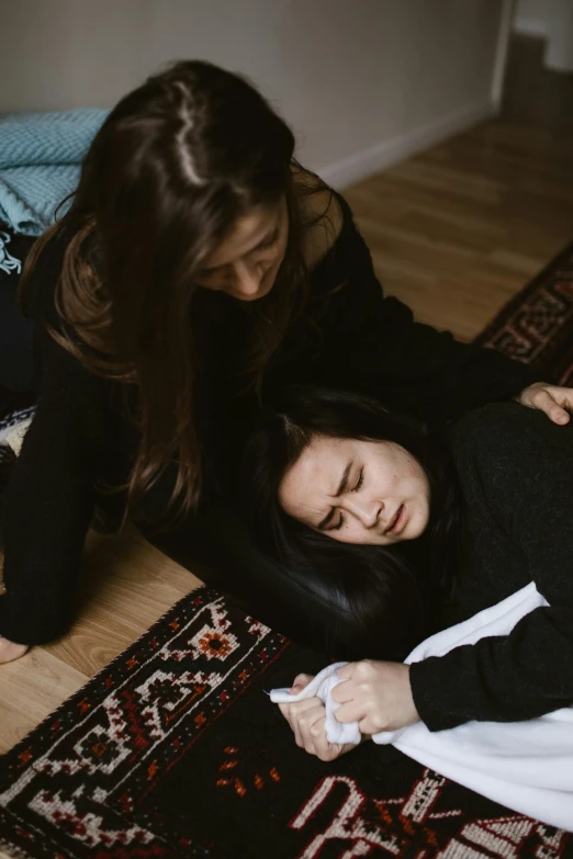 a couple of women laying on top of a wooden floor, a picture, by Elsa Bleda, trending on pexels, hurufiyya, first aid kit, woman crying, gif, edmund blair and charlie bowater