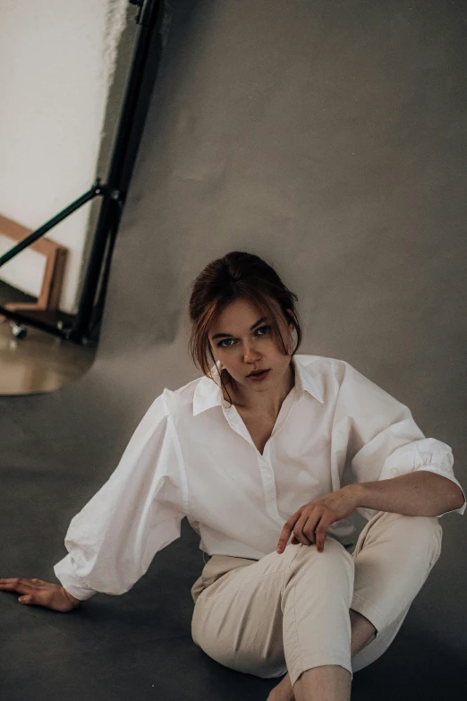 a woman sitting on the ground in a white shirt, by irakli nadar, trending on pexels, renaissance, hailee steinfeld, on a white table, cinematic. by leng jun, androgyny