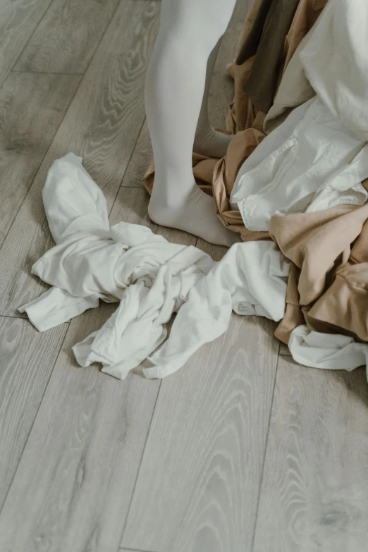 a pile of clothes sitting on top of a wooden floor, inspired by Sarah Lucas, pexels contest winner, renaissance, wearing white tights, made of lab tissue, beige colors, chaos