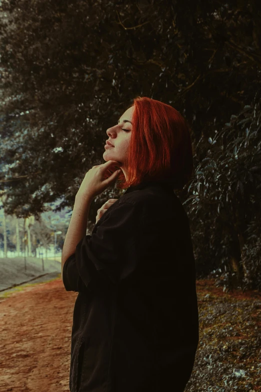 a woman with red hair standing on a dirt road, an album cover, inspired by Elsa Bleda, pexels contest winner, realism, in a city park, profile image, woman in black robes, red short hair