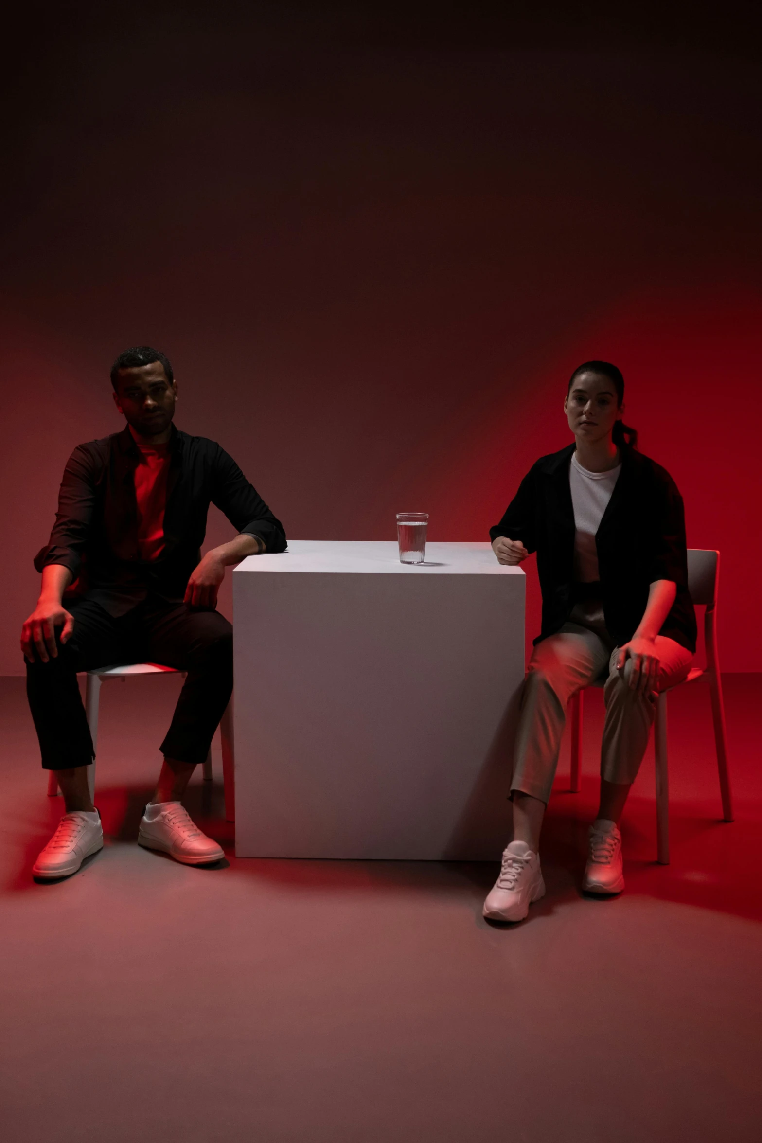 two men sitting at a table in front of a red light, an album cover, inspired by Wang Duo, pexels contest winner, ignant, standing still, bowater charlie and brom gerald, light room