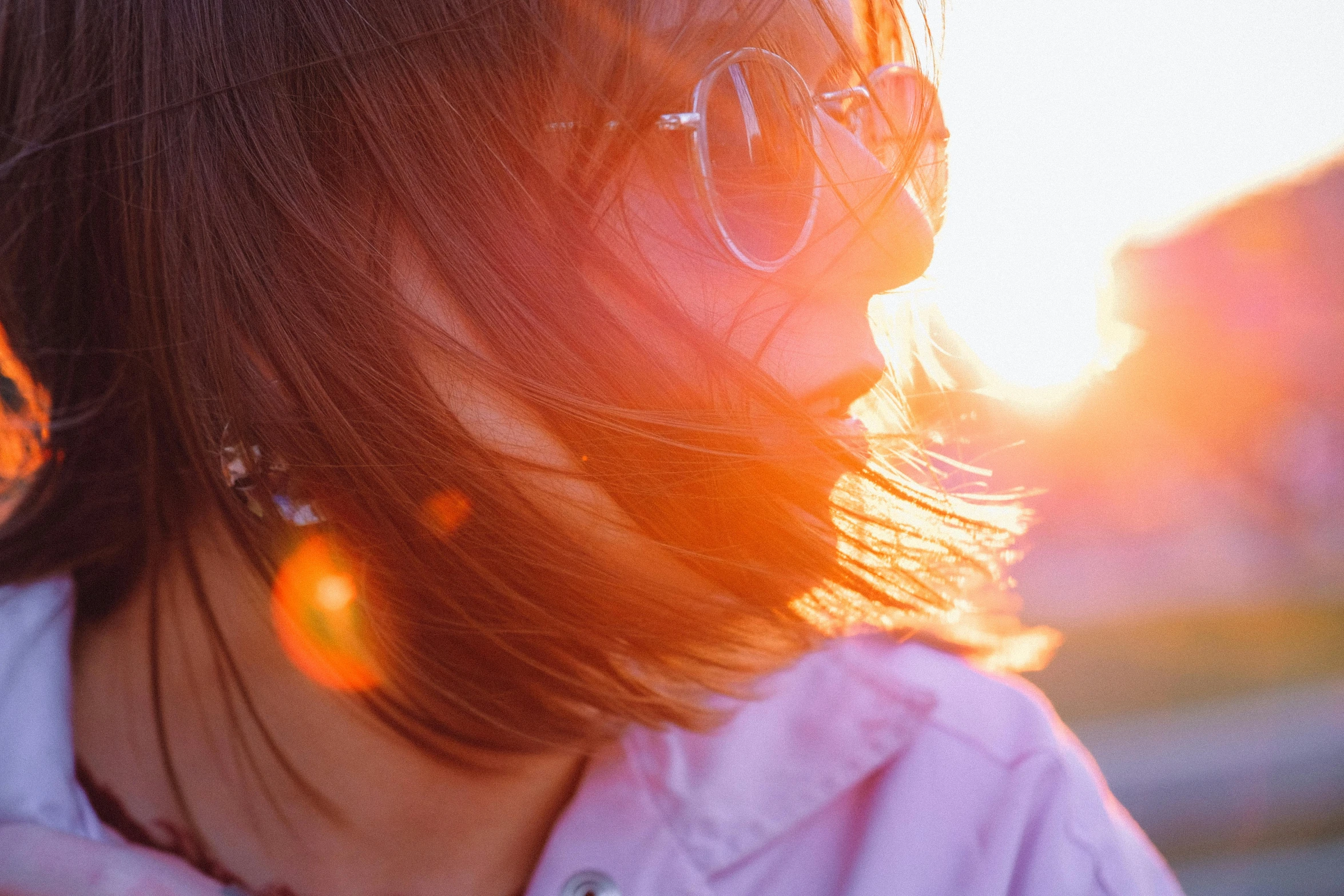 a close up of a person wearing glasses, trending on pexels, sunset halo around her head, young asian girl, thinning hair, bright sunny time