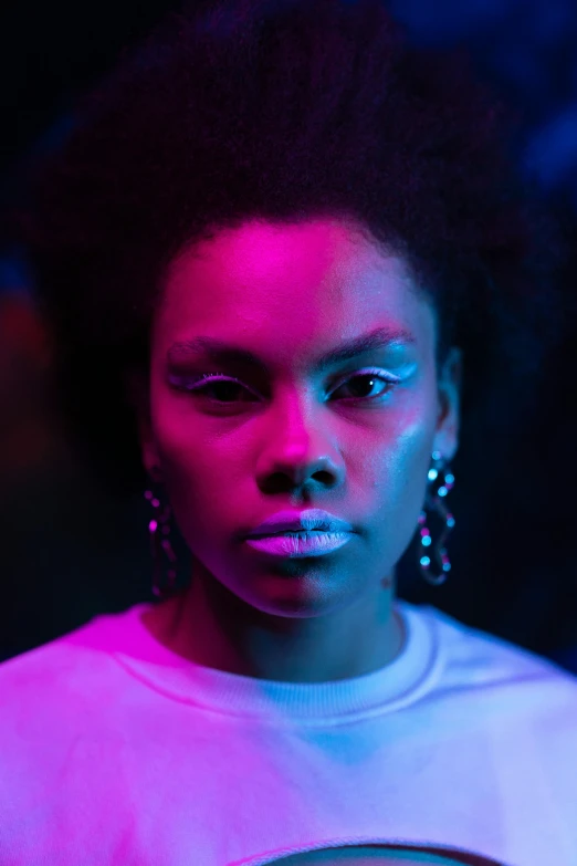 a woman standing in front of a neon light, pexels, afrofuturism, blue symmetric eyes 24yo, smug look, afropunk, perfectly lit. movie still