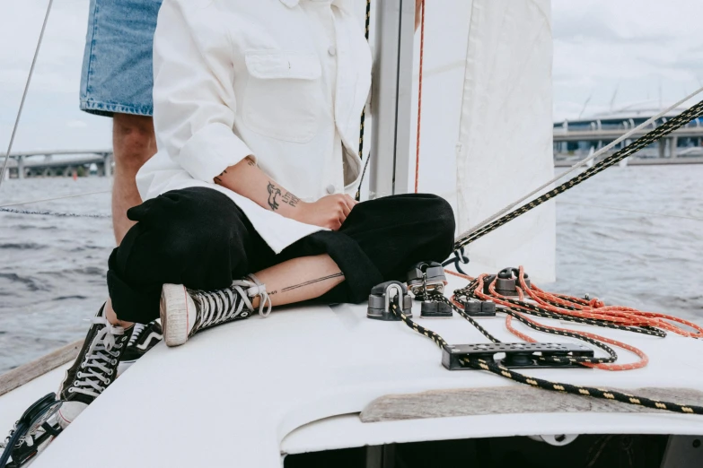 a woman sitting on the bow of a sailboat, pexels contest winner, streetwear, shows a leg, sharpie, off - white collection