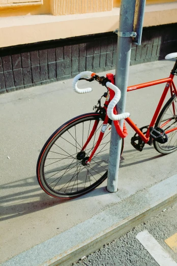 a red bike is chained to a pole, unsplash, photorealism, white and orange, complex design, high angle, fujicolor photo