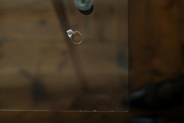 a couple of rings sitting on top of a glass table, inspired by Cornelia Parker, unsplash, hyperrealism, old experimentation cabinet, scratches on photo, 4 k close up, single panel