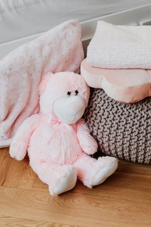 a pink teddy bear sitting next to a pile of blankets, detailed product image, detail shot, maternal, glimmering