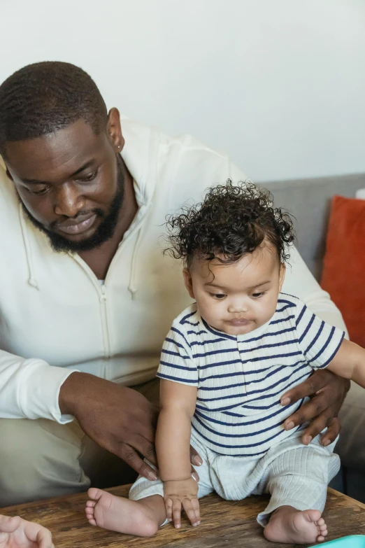 a man and woman sitting on a couch with a baby, pexels contest winner, incoherents, a black man with long curly hair, father with child, gif, reading