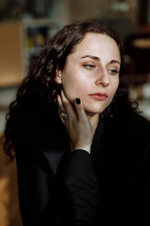 a woman sitting in a chair with her hand on her face, inspired by Anita Malfatti, trending on pexels, photorealism, neri oxman, hand on her chin, pale skin and dark eyes, concert