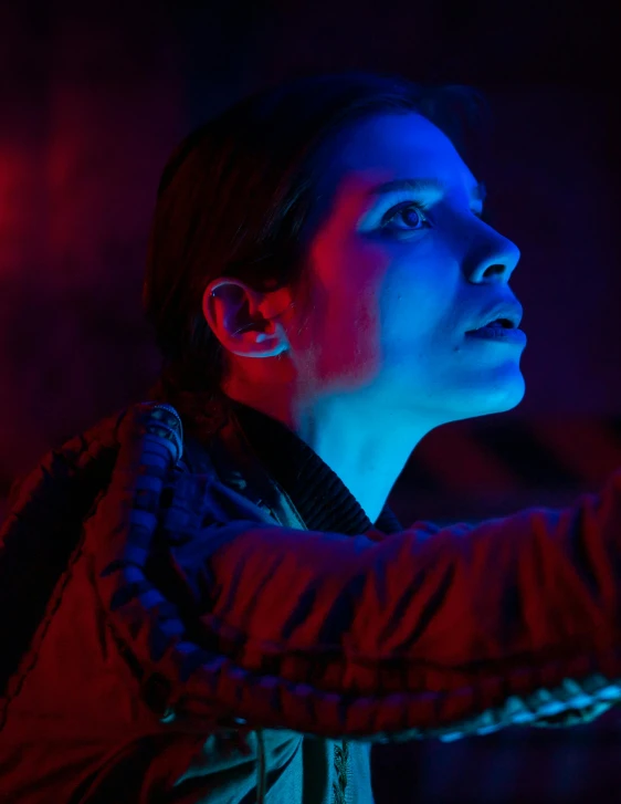 a woman holding a nintendo wii controller in a dark room, inspired by Elsa Bleda, unsplash, video art, in an colorful alien planet, blue and red lighting, woman's face looking off camera, still from movie dune