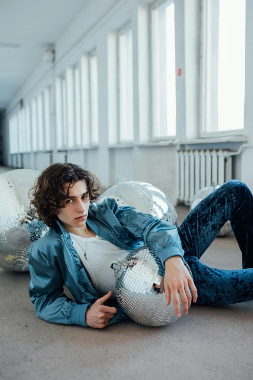 a man laying on the ground with a disco ball, by Cosmo Alexander, trending on pexels, hyperrealism, timothee chalamet, wearing a jeans jackets, curls, modeling studio