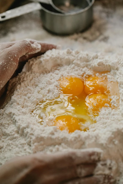 a close up of a person preparing food on a table, covered in white flour, raw egg yolks, precious moments, manuka