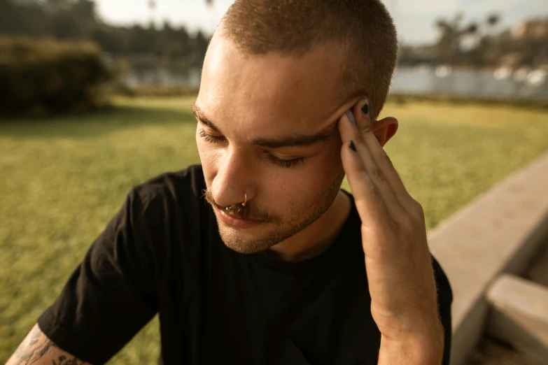 a man sitting on a bench talking on a cell phone, inspired by Seb McKinnon, trending on pexels, realism, thin scar on his forehead, septum piercing, tiny thin mustache, forehead jewelry