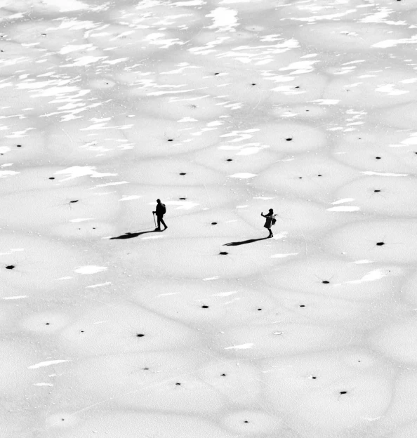 a couple of people walking across a snow covered field, a black and white photo, by Zsolt Bodoni, unsplash contest winner, minimalism, birds eye view, 8 k, summer sunlight, bo xun ling
