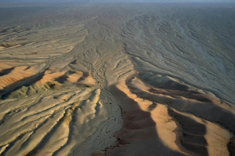 an aerial view of sand dunes in the desert, an album cover, pexels contest winner, land art, erosion channels river, low light, nat geo, volcanic