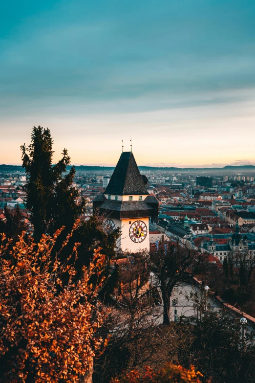 a clock tower in the middle of a city, a picture, by Karl Stauffer-Bern, trending on pexels, art nouveau, city lights made of lush trees, nuremberg, hills, warm light