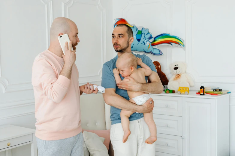 a man talking on a cell phone while holding a baby, by Julia Pishtar, pexels contest winner, modernism, vitaly bulgarov and mike nash, as well as the handyboy, gay, bald