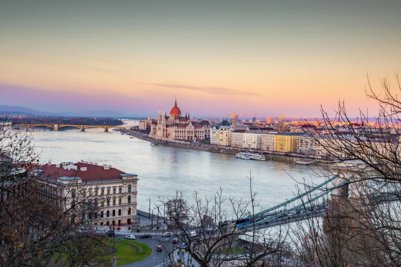 a bridge over a river with a city in the background, by Konrad Witz, pexels contest winner, golden hour hues, parliament, panoramic shot, austro - hungarian