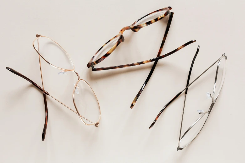 three pairs of glasses on a white surface, by Matija Jama, trending on pexels, square glasses, various items, thin lines, sustainable materials