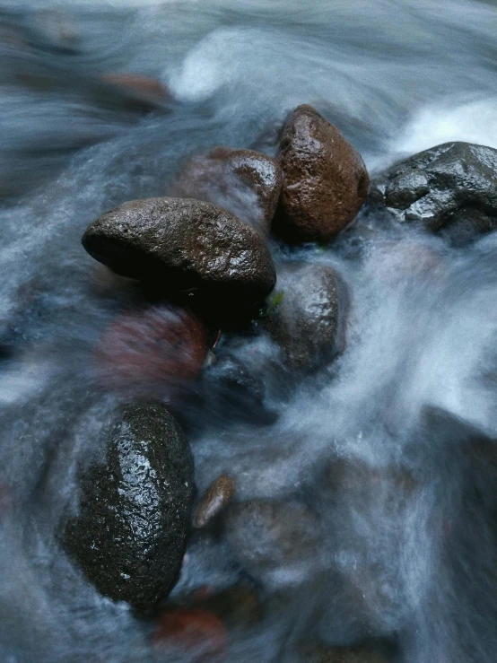 a group of rocks sitting on top of a river, rushing water, award-winning photograph, medium format, ((rocks))