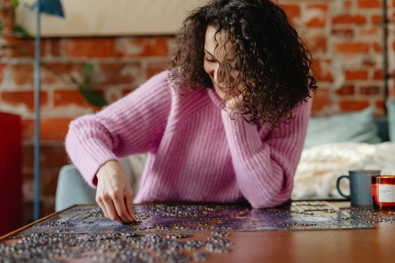 a woman sitting at a table with a puzzle, a jigsaw puzzle, by Julia Pishtar, pexels contest winner, wearing a purple sweatsuit, wearing a dress made of beads, brunette, gif