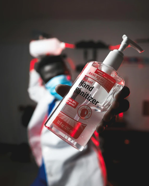 a person in a lab coat holding a bottle of hand sanitizer, pexels contest winner, white and red body armor, indonesia, bong, lgbtq