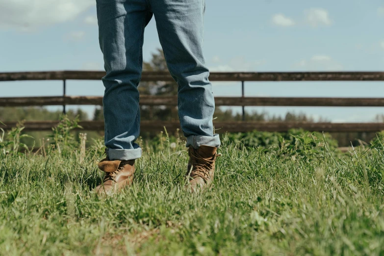 a man standing on top of a lush green field, an album cover, by Jessie Algie, trending on pexels, jeans and boots, gum rubber outsole, gardening, 8 0 mm photo