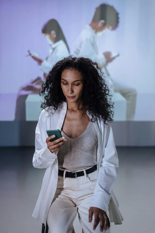 a woman sitting on a chair looking at her cell phone, a hologram, by Sebastian Vrancx, trending on pexels, renaissance, with a lab coat, curly haired, on display, model is wearing techtical vest