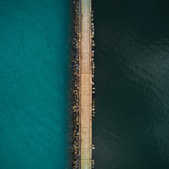 a group of people standing on a pier next to a body of water, by Ibrahim Kodra, pexels contest winner, minimalism, aerial perspective, brown and cyan blue color scheme, split in half, road to the sea