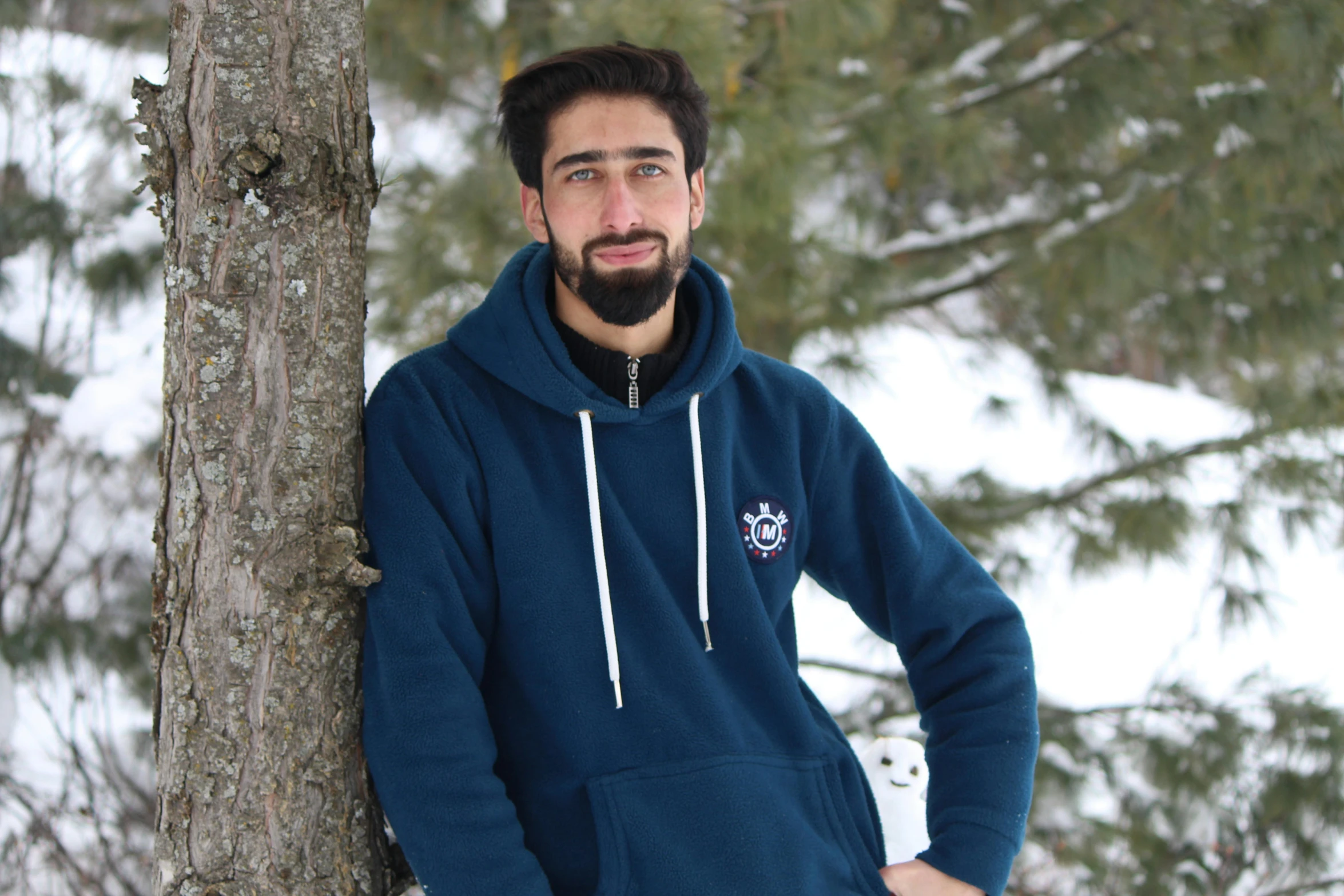 a man leaning against a tree in the snow, a portrait, inspired by Abdullah Gërguri, pexels contest winner, hurufiyya, in a navy blue sweater, discord profile picture, programming, graduation photo