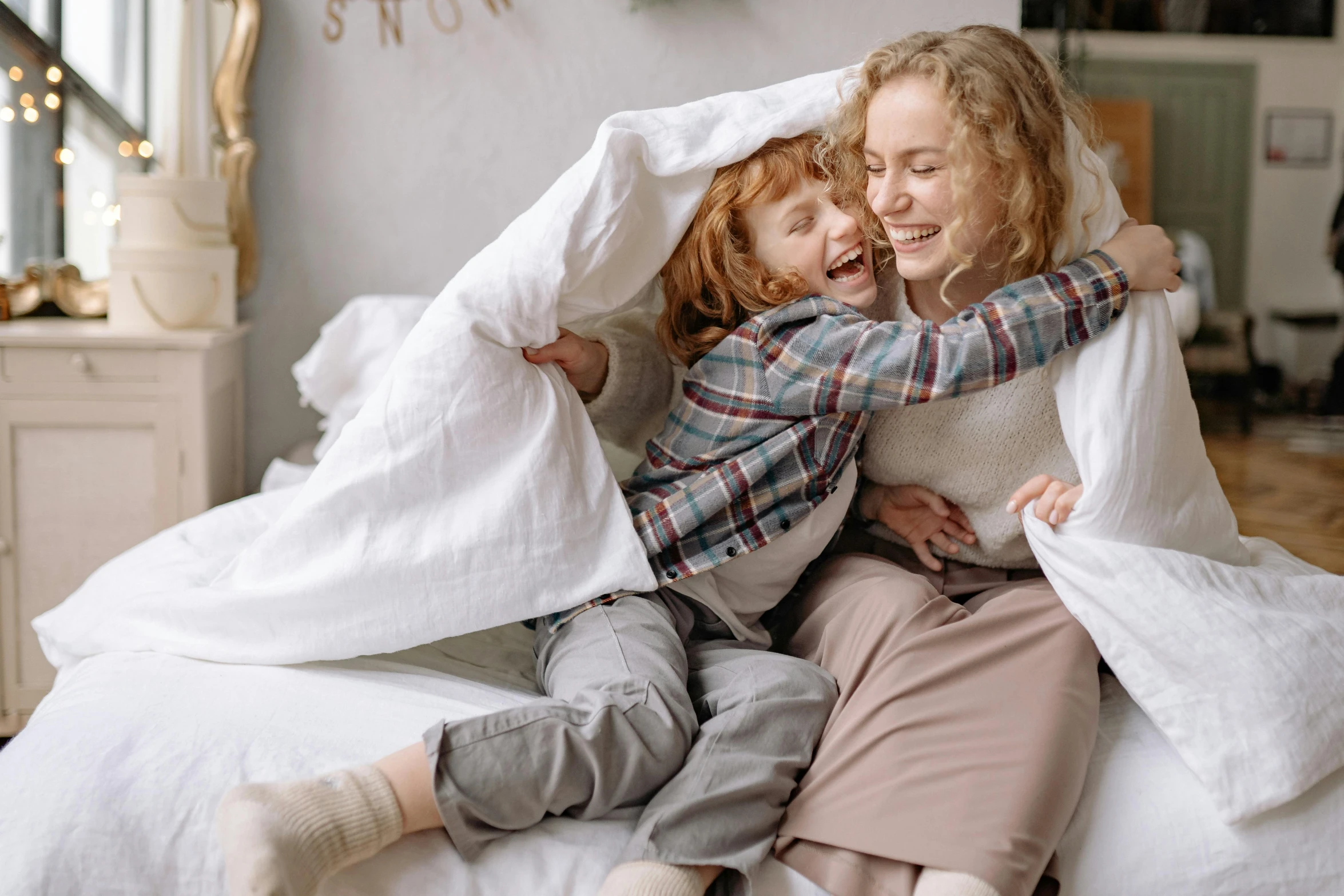 a couple of women sitting on top of a bed, pexels contest winner, happening, happy kid, ( redhead, hugging each other, curled up under the covers