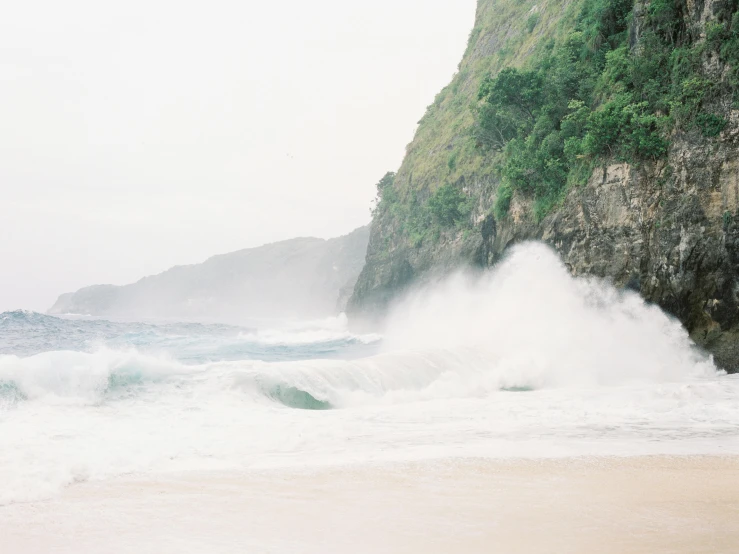 a man riding a wave on top of a sandy beach, pexels contest winner, visual art, mist from waterfall, 2 5 6 x 2 5 6 pixels, vsco film grain, coastal cliffs