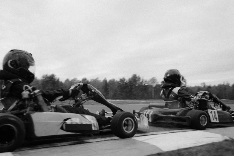 a group of people riding karts on top of a race track, a black and white photo, by Jaakko Mattila, photographic print, low quality footage, mod, old footage