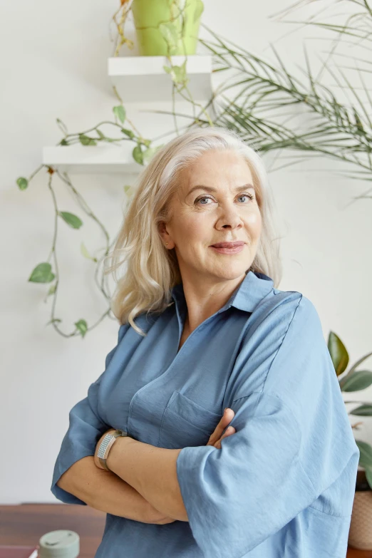 a woman sitting at a table with her arms crossed, inspired by Louisa Matthíasdóttir, white hair color, next to a plant, confident looking, on clear background