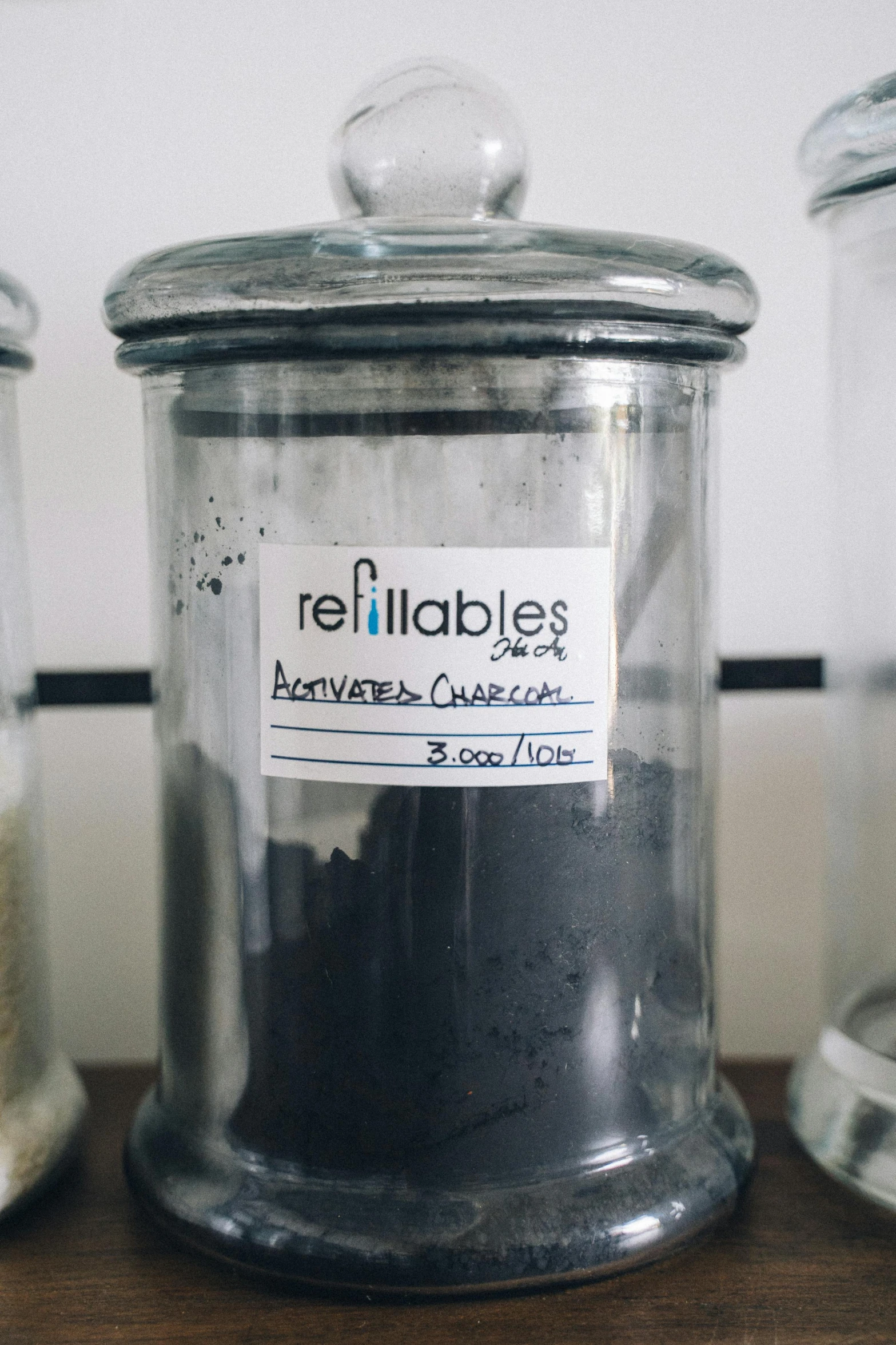 three glass jars sitting on top of a wooden table, by Arabella Rankin, reddit, medical labels, charcoal, synthetic materials, battery