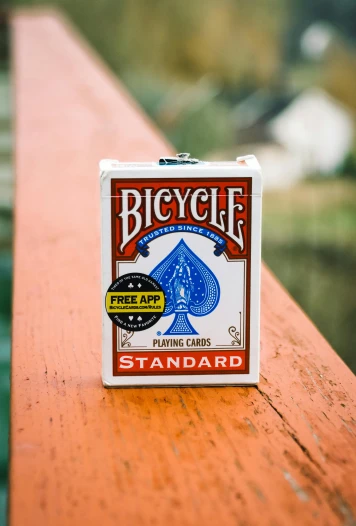 a bicycle playing card sitting on top of a wooden table, white box, hollywood standard, detailed product image, hanging