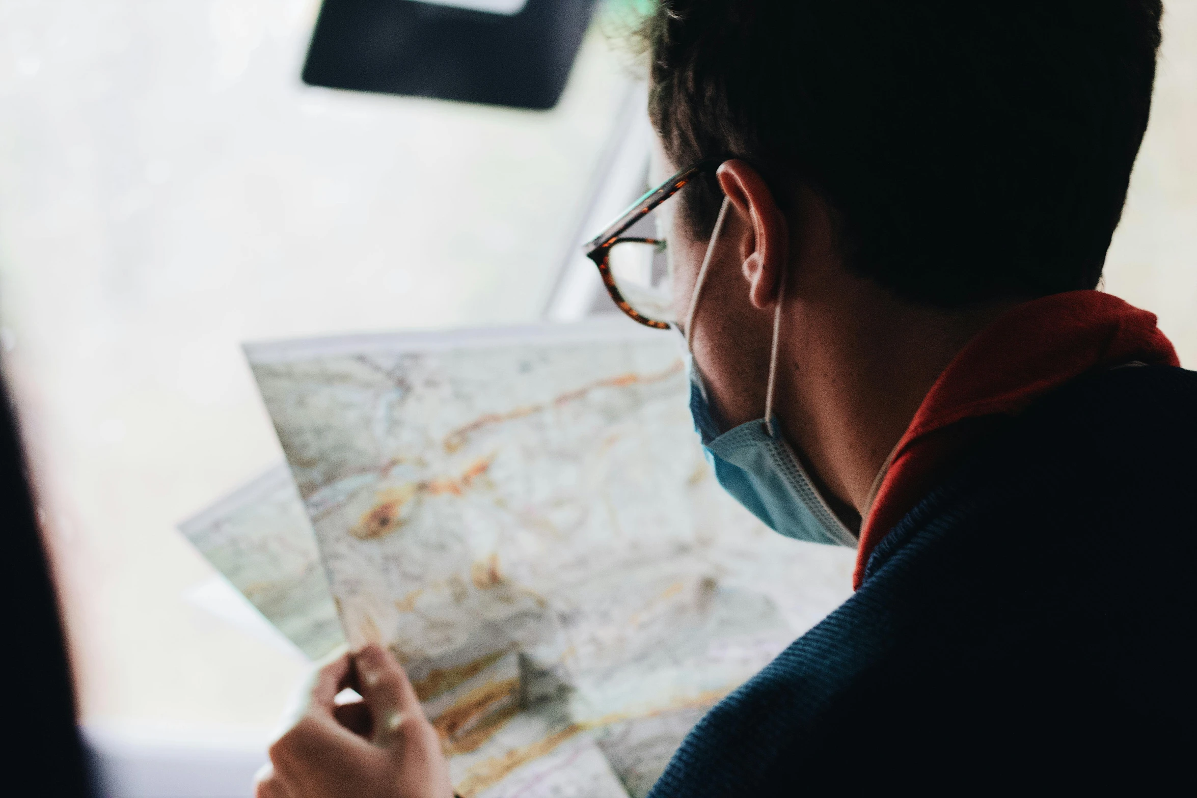 a man wearing a face mask looking at a map, pexels contest winner, 🚿🗝📝, navigator glasses, avatar image, man sitting facing away