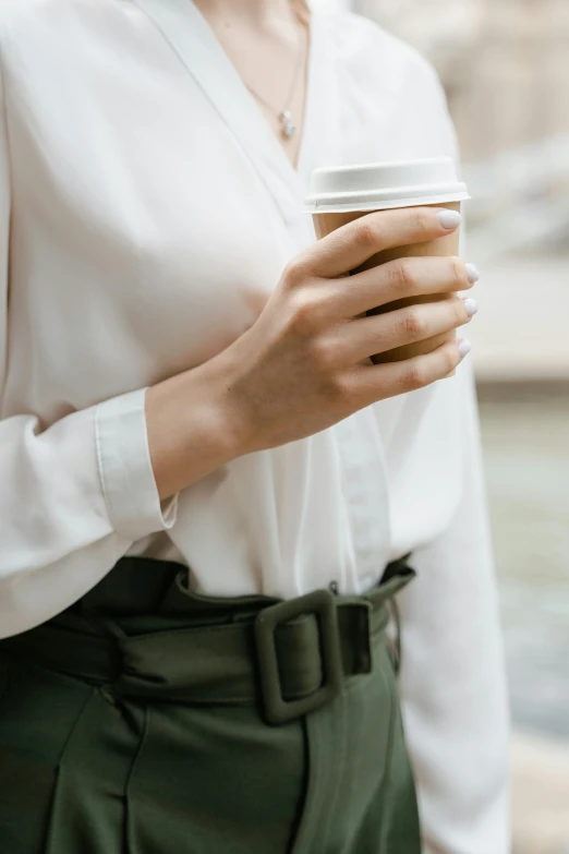 a woman in a white shirt holding a cup of coffee, by Nina Hamnett, trending on unsplash, renaissance, tailored clothing, multiple stories, visible belly, bag over the waist