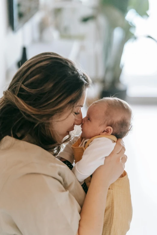 a woman holding a baby in her arms, pexels contest winner, kissing smile, scientific study, lightly dressed, brunette