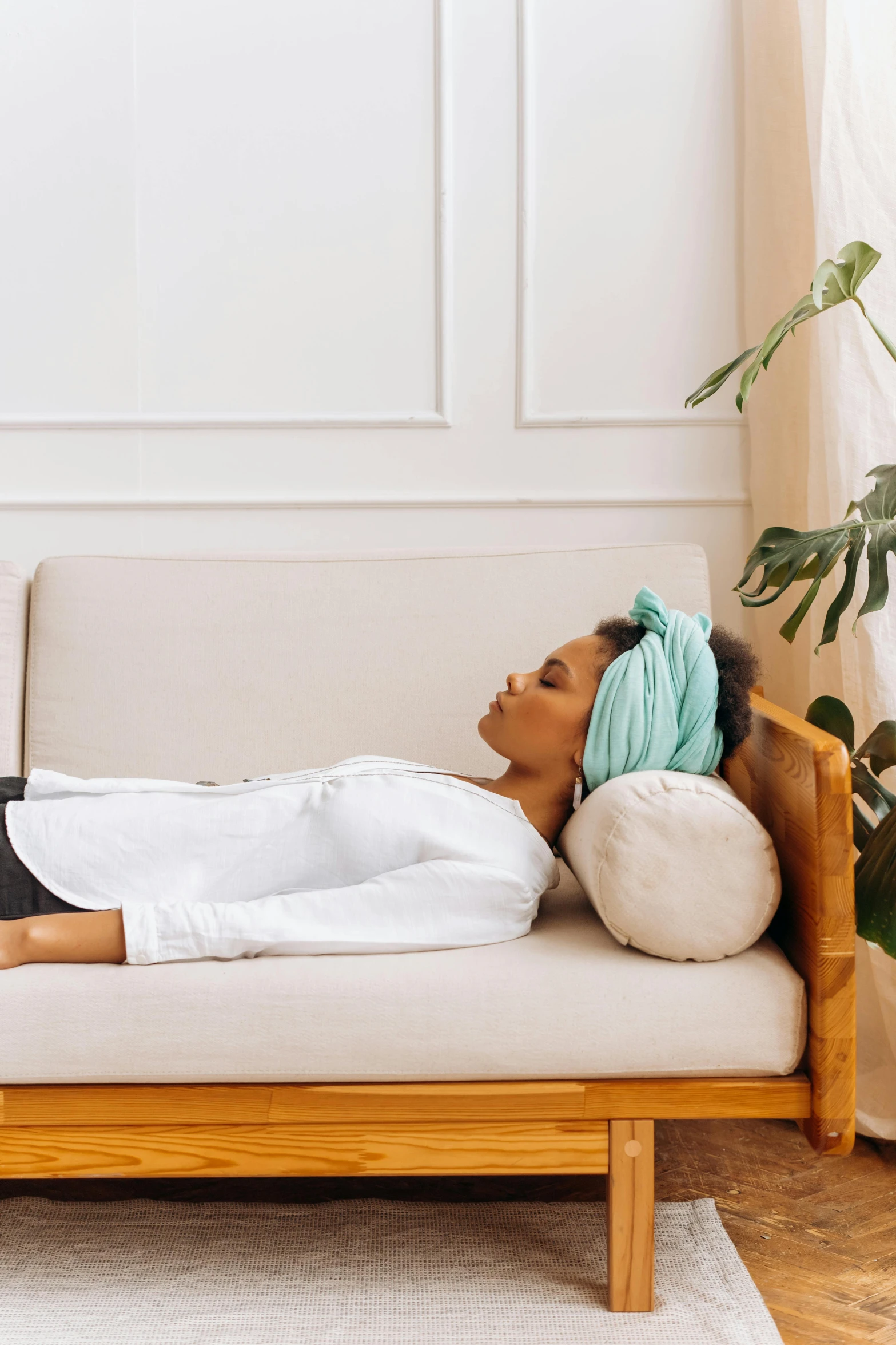 a woman laying on a couch in a living room, by Julia Pishtar, trending on pexels, renaissance, cloth head wrap, healing tubes, soft green natural light, healing pods