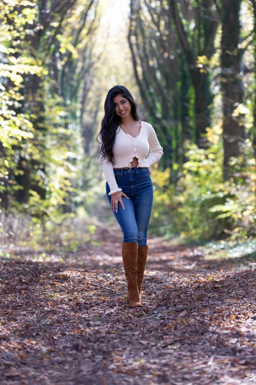 a woman walking down a path in the woods, jeans and boots, regal pose, alanis guillen, wears brown boots