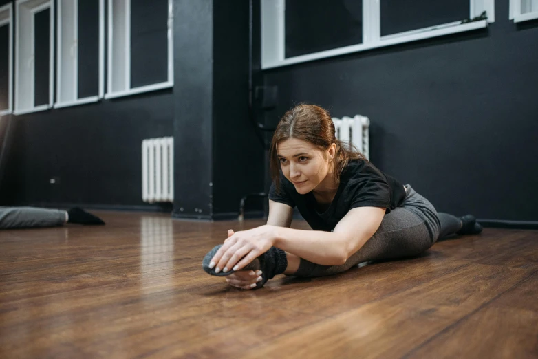 a woman laying on the floor with a remote control, by Emma Andijewska, unsplash, local gym, low quality photo, crouching, stretch